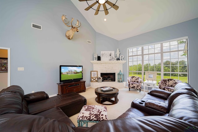 carpeted living area with a ceiling fan, high vaulted ceiling, visible vents, and a stone fireplace