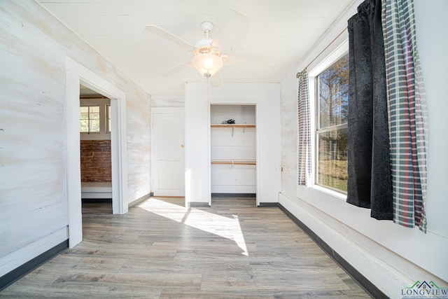 unfurnished bedroom featuring a ceiling fan, baseboards, wood finished floors, and a closet