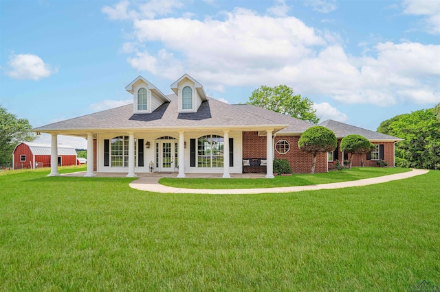 view of front of home with roof with shingles, an outbuilding, a front lawn, and brick siding