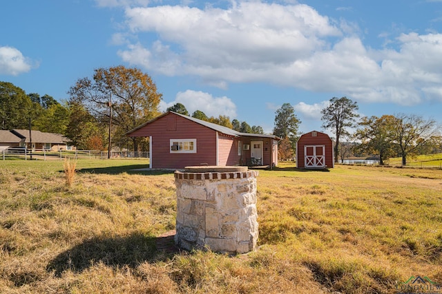 view of home's exterior featuring a storage unit, a lawn, fence, and an outbuilding