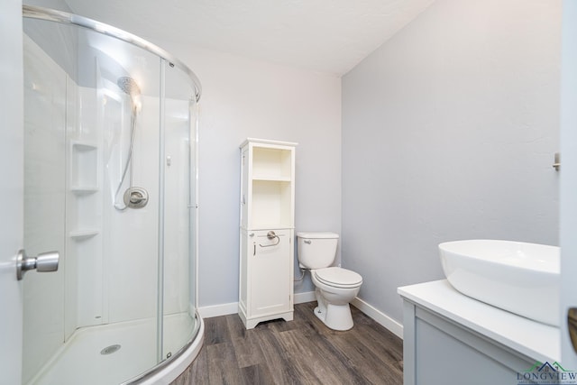 full bath with a shower stall, wood finished floors, vanity, baseboards, and toilet