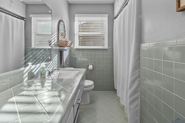 bathroom with tile patterned floors, vanity, tile walls, and toilet