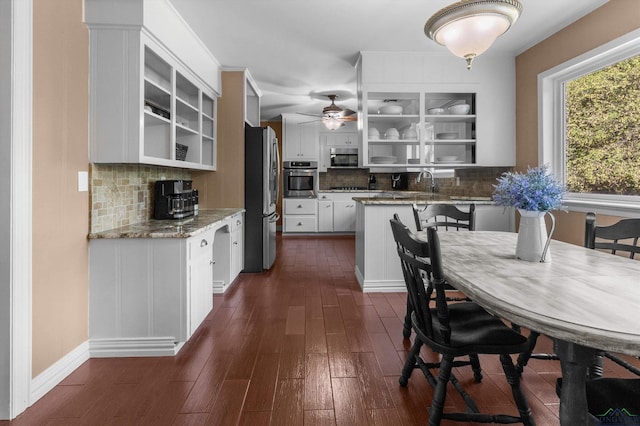 kitchen featuring appliances with stainless steel finishes, dark hardwood / wood-style flooring, tasteful backsplash, light stone counters, and white cabinets