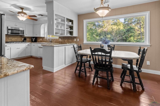 kitchen with backsplash, dark wood-type flooring, light stone counters, white cabinetry, and stainless steel appliances