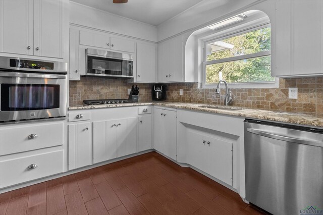 kitchen with light stone countertops, sink, tasteful backsplash, white cabinets, and appliances with stainless steel finishes