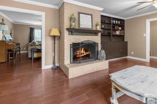 living room featuring crown molding, ceiling fan, dark hardwood / wood-style floors, and a brick fireplace