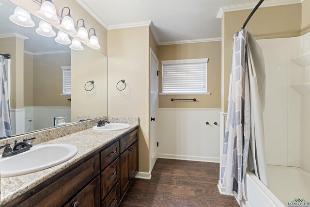 1130 Oakwood St, Carthage, TX 75633 - full bath with wood finished floors, double vanity, toilet, shower / bath combo, and ornamental molding