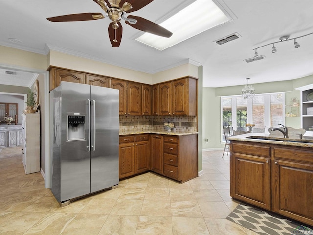 kitchen with stainless steel fridge, tasteful backsplash, ceiling fan with notable chandelier, sink, and pendant lighting