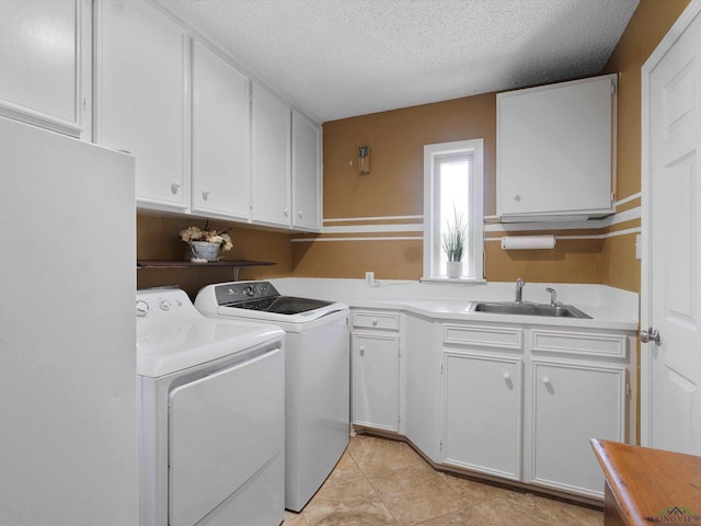 laundry room featuring sink, cabinets, separate washer and dryer, a textured ceiling, and light tile patterned flooring