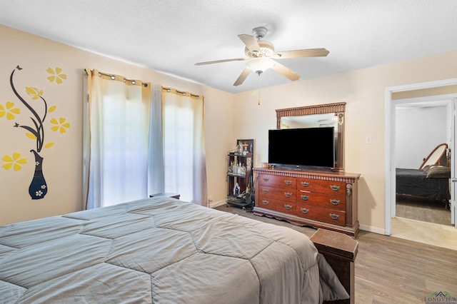 bedroom with a textured ceiling, wood finished floors, a ceiling fan, and baseboards