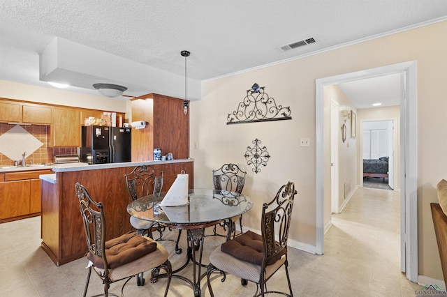 dining space with a toaster, visible vents, ornamental molding, a textured ceiling, and baseboards