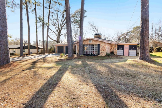 mid-century home featuring a garage, a chimney, a front lawn, and brick siding