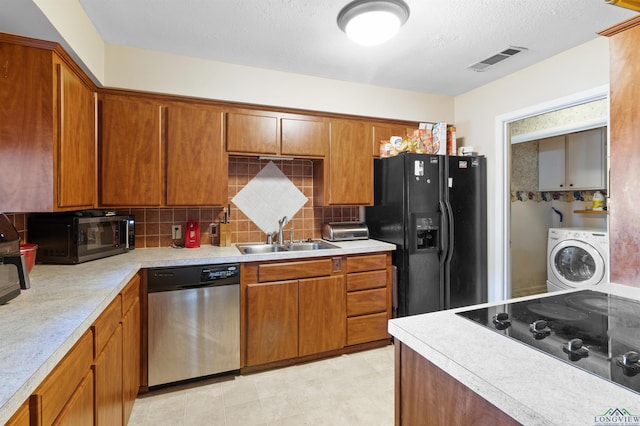 kitchen with black appliances, washer / clothes dryer, light countertops, and a sink