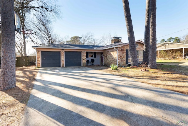 mid-century home featuring brick siding, a chimney, fence, a garage, and driveway