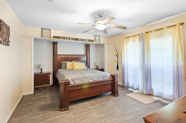 bedroom featuring multiple windows, wood finished floors, and baseboards