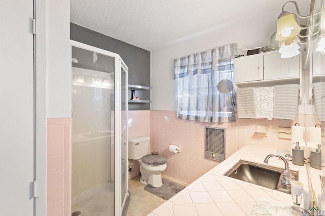 full bath with tile walls, heating unit, toilet, a stall shower, and a textured ceiling