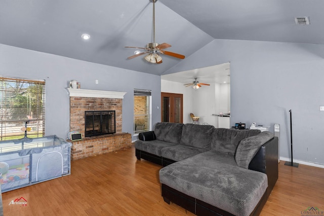 living room with ceiling fan, a fireplace, wood-type flooring, and lofted ceiling