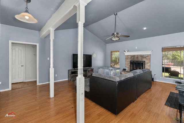 living room featuring lofted ceiling, a brick fireplace, hardwood / wood-style flooring, ceiling fan, and ornate columns