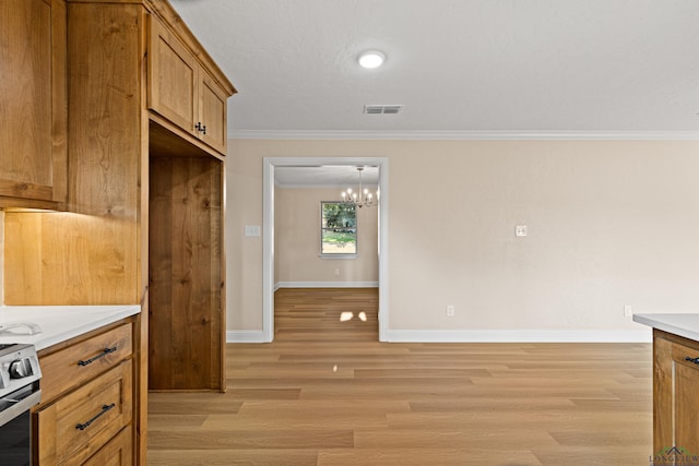 kitchen featuring crown molding, light hardwood / wood-style flooring, stainless steel stove, and an inviting chandelier