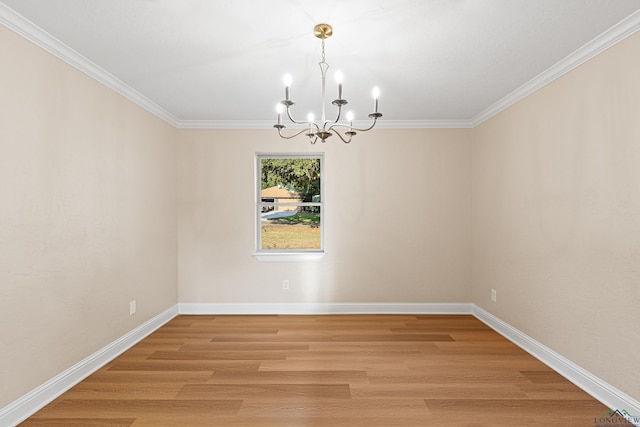 spare room featuring wood-type flooring, an inviting chandelier, and crown molding