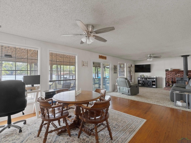 3065 E Lake, Gladewater, TX 75647 - dining space featuring a ceiling fan, a wood stove, a textured ceiling, wood finished floors, and an office area