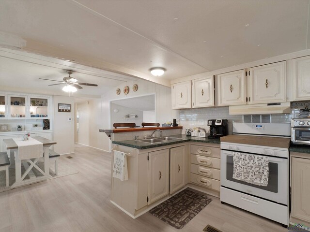 3065 E Lake, Gladewater, TX 75647 - kitchen featuring white electric range oven, under cabinet range hood, a peninsula, and white cabinetry