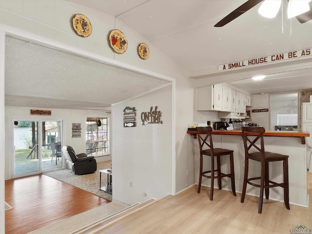 3065 E Lake, Gladewater, TX 75647 - kitchen with light wood finished floors, lofted ceiling, a breakfast bar, white cabinets, and a ceiling fan