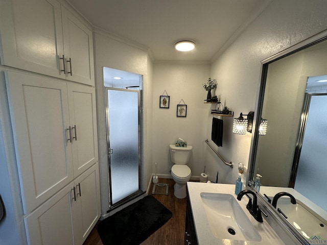 bathroom featuring vanity, wood-type flooring, ornamental molding, a shower with shower door, and toilet