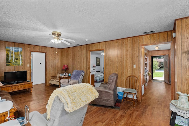 living room featuring ceiling fan, hardwood / wood-style floors, and a textured ceiling