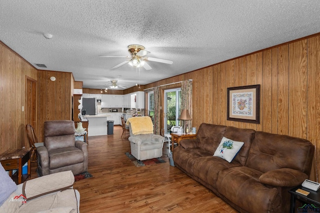 living room featuring ceiling fan, hardwood / wood-style floors, and wooden walls