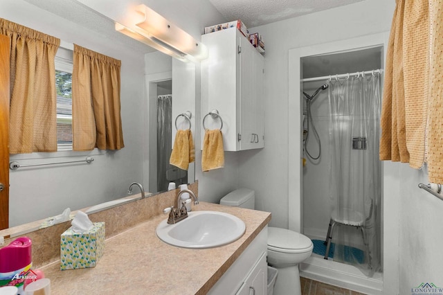 bathroom with vanity, toilet, a textured ceiling, and walk in shower