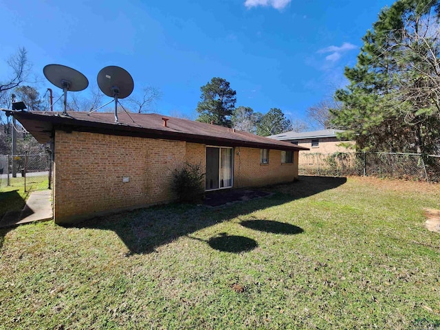 back of property featuring brick siding, fence, and a lawn