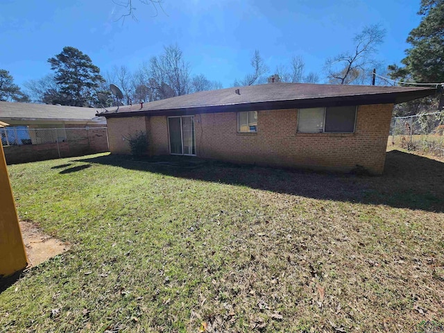 back of house featuring brick siding, fence, and a lawn