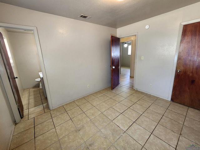 unfurnished bedroom with light tile patterned floors and visible vents