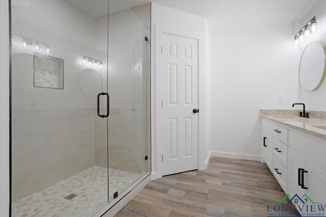 bathroom featuring hardwood / wood-style floors, vanity, and a shower with door