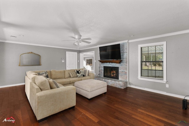 living room with a brick fireplace, dark hardwood / wood-style floors, ceiling fan, ornamental molding, and a textured ceiling