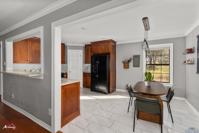 kitchen with black fridge with ice dispenser, backsplash, hanging light fixtures, and crown molding