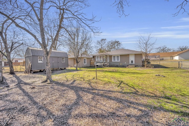 rear view of property featuring a lawn and a storage shed