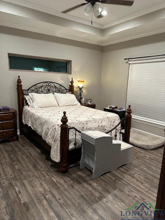 bedroom featuring ceiling fan, dark hardwood / wood-style flooring, ornamental molding, and a tray ceiling