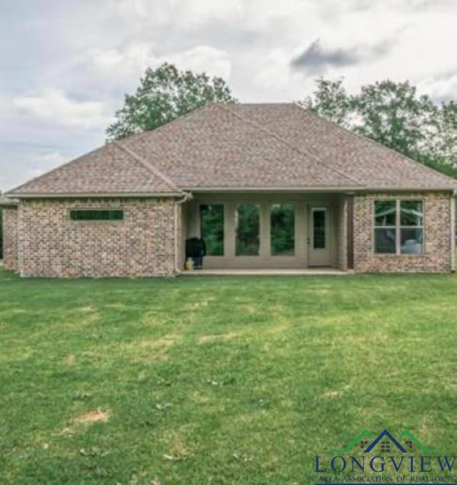 489 N Sanders St, White Oak, TX 75693 - rear view of house featuring brick siding and a lawn