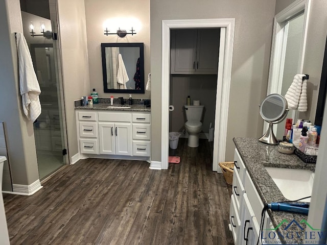 bathroom featuring wood-type flooring, vanity, toilet, and a shower with shower door