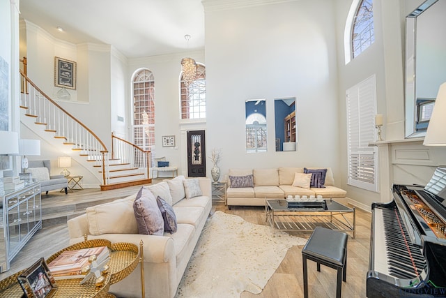 living area with stairs, wood finished floors, a towering ceiling, and ornamental molding