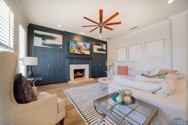 living room with visible vents, light wood finished floors, recessed lighting, a high end fireplace, and ornamental molding