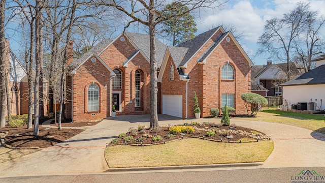 view of front of home with central air condition unit, a front lawn, curved driveway, an attached garage, and brick siding