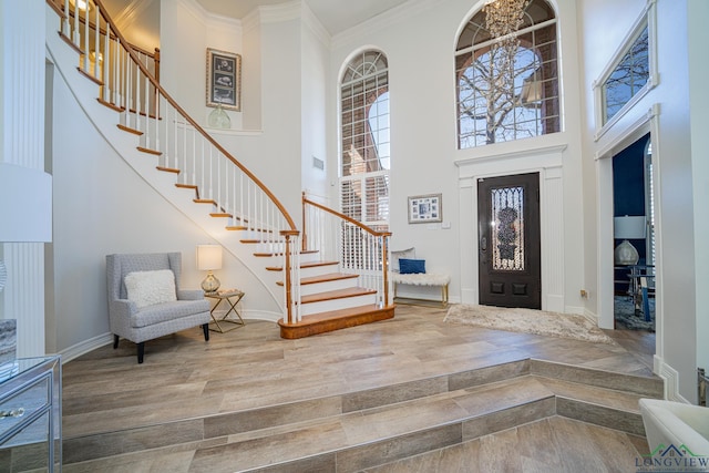 entryway with stairway, ornamental molding, a high ceiling, and wood finished floors