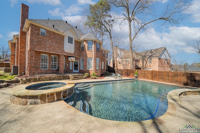 view of swimming pool with a pool with connected hot tub, a patio, and fence