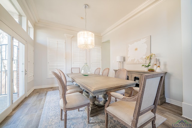 dining space with light wood finished floors, a chandelier, baseboards, and ornamental molding