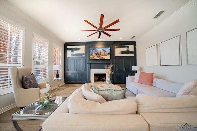 living area with baseboards, visible vents, a high end fireplace, and ornamental molding