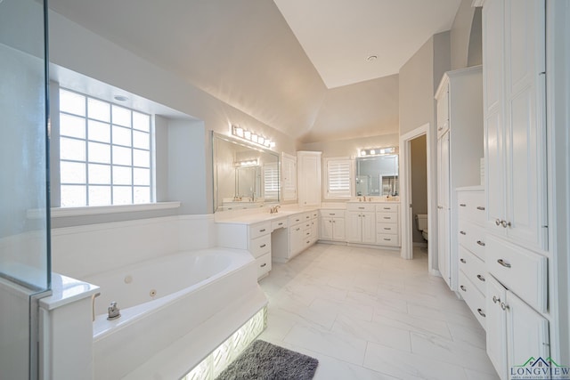 full bathroom with toilet, marble finish floor, vanity, lofted ceiling, and a whirlpool tub