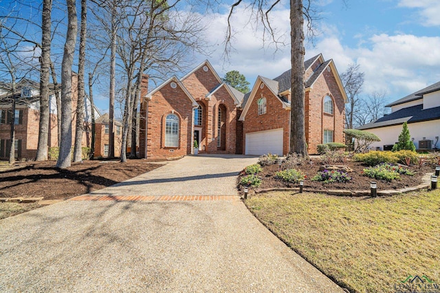 traditional-style home with cooling unit, driveway, an attached garage, a chimney, and brick siding